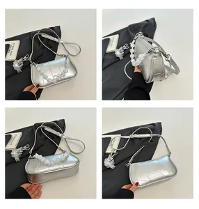 Dettagli di una borsa a tracolla argento metallizzato con manico di perle e cuciture