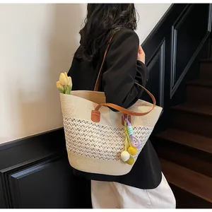 Detail of hand-woven straw tote with hollow patterns, brown leather straps and colorful charms