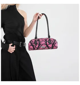 Detailed close-up of pink and black snakeskin texture and silver logo plate on handbag