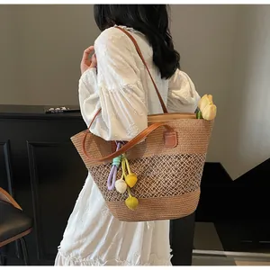 Detail of woven straw tote bag with brown leather straps and floral charm accents