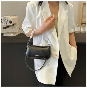 Dettaglio borsa squadrata nera con perle decorative e finiture metalliche argento