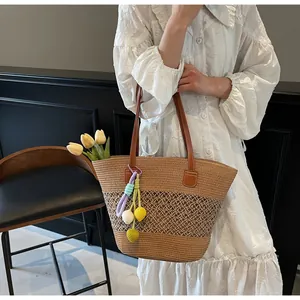 Detail of hand-woven straw tote bag with leather straps and colorful tulip charm