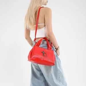 Borsa a tracolla gotica in pelle rossa con ciondolo a croce e catene, indossata da una modella