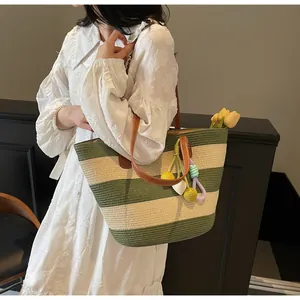 Detail of striped woven tote bag with green accents and decorative floral pom-pom charms
