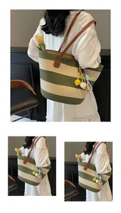 Detail of green and beige striped woven tote bag with brown leather straps and floral charm