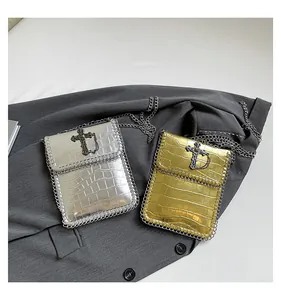 Detail of gold and silver crocodile textured mini phone bags with punk metal cross and chains