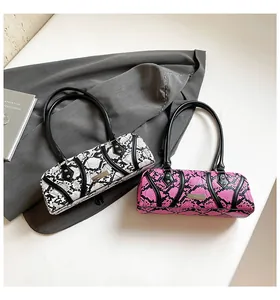 Detailed view of two snakeskin pattern Boston bags with metal rivets and long handles