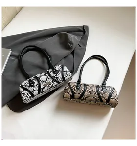 Close-up of cylindrical shoulder bag showing detailed snake print and black handles