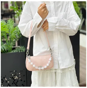 Dettaglio della borsa a tracolla rosa con catena di perle bianche e trama goffrata