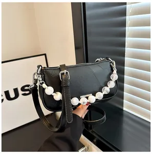 Dettaglio borsa nera in pelle testurizzata con manico decorativo in perle di marmo