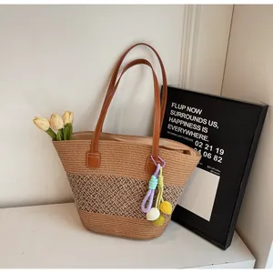 Detail of woven tote bag featuring striped texture, leather straps and charm accent