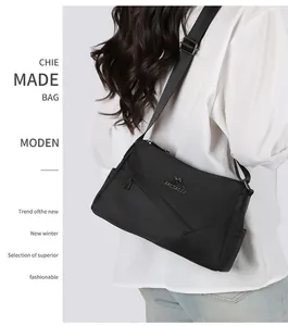 Détail d'un sac d'affaires noir avec bandoulière réglable et logo métallique de luxe