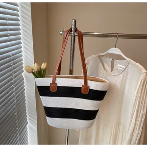 Detail of black and white striped woven tote bag with brown leather shoulder straps