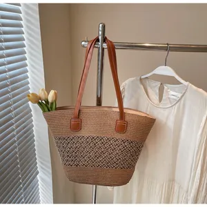 Detail of striped woven straw tote bag with brown leather handles and rustic texture