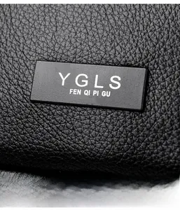 Detailansicht der schwarzen Lederhandtasche mit Litschi-Struktur und YGLS-Logo-Plakette