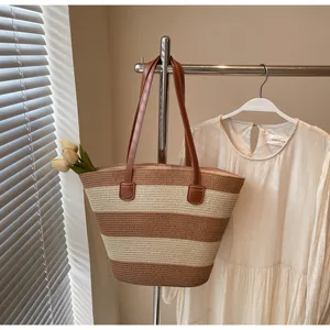 Detail of striped straw tote bag with brown leather handles and decorative tulips