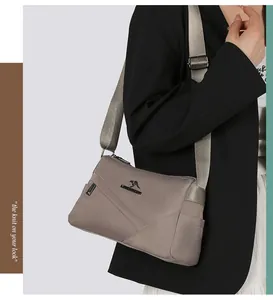 Détail du sac bandoulière en nylon gris-brun avec sangle réglable et logo kangourou en métal