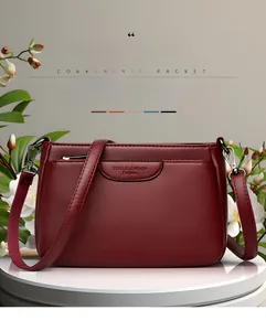 Close-up of wine red litchi grain leather crossbody bag with decorative front pocket