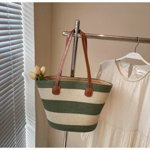 Detail of green and white striped woven tote bag with premium brown leather handle