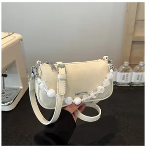 Dettaglio della borsa a tracolla bianco crema con motivo trapuntato e tracolla di perle