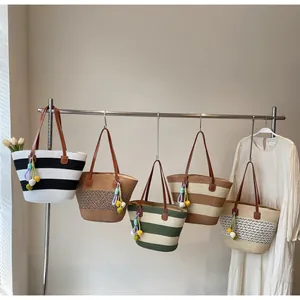 Detail of woven straw tote bags in various stripes with colorful pompom tassels