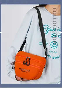 Detail of orange nylon crossbody bag showing three zippered layers and wide strap