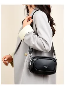 Seitenansicht einer schwarzen Damen-Umhängetasche mit Lychee-Struktur zum grauen Blazer