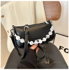 Dettaglio della borsa in pelle nera martellata con eleganti perle effetto marmo