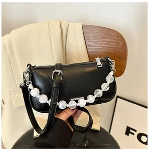 Dettaglio della borsa a tracolla in pelle nera con elegante catena di perle bianche