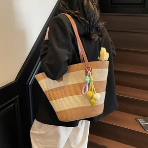 Striped woven straw tote bag with shoulder straps and colorful decorative charms