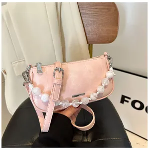 Dettaglio borsa a tracolla rosa con catena di perle marmorizzate e hardware argento