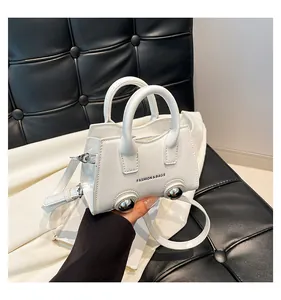 Close-up of white small square bag with silver metal ball rivets and text detail
