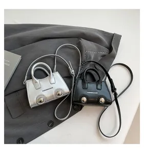 Detail of mini trapezoid handbags in black and silver with metal rivets and fashion print