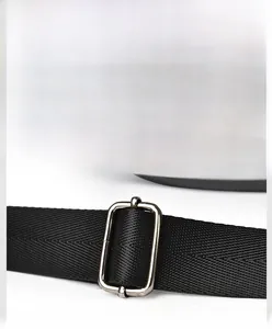Détail du logo en métal et de la boucle de sangle sur un sac à bandoulière noir