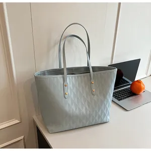 Detail of light blue quilted tote bag with gold metal buckle and zipper on a white desk