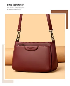 Detail of red pebbled leather shoulder bag with zipper pocket and adjustable strap