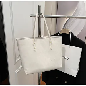 Detailed close-up of white quilted tote bag featuring golden metal rivets and textures