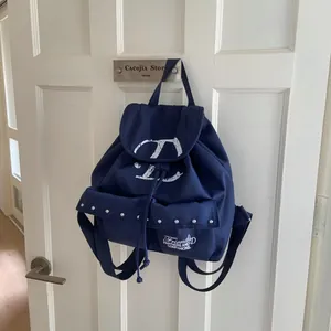 Detail of dark blue vintage canvas backpack with D logo and metal rivets on front pockets