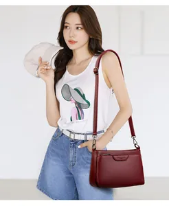 Detail of dark red lychee grain leather crossbody bag with decorative zipper and strap