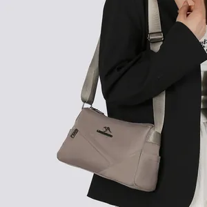 Sac à bandoulière en nylon taupe avec large sangle et design à plusieurs zips