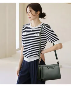 Detail view of dark green leather small square bag with adjustable shoulder strap