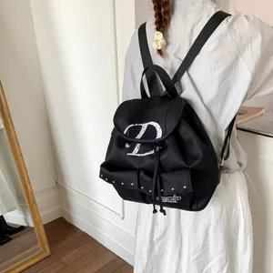 Black nylon backpack with white letter print and silver rivet pockets for daily school use