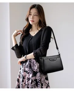 Close-up of black lychee-grain leather crossbody bag worn by a model in casual attire
