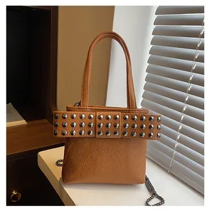 Détail du nœud riveté sur un sac à main en cuir grainé caramel avec chaîne