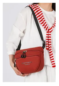 Detail of red nylon crossbody bag showing dual zippers and adjustable black strap