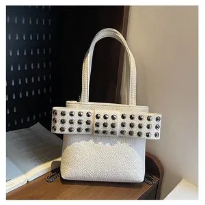 Gros plan d'un sac en cuir blanc avec nœud géant clouté et bandoulière en chaîne