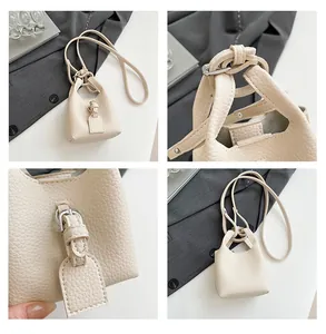 Nahaufnahme der beigen Ledertextur mit Litchi-Prägung und Metallschnalle der Mini-Tasche