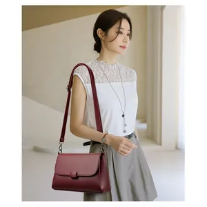 Elegante weinrote Umhängetasche aus Leder, getragen von einem Modell in Innenräumen