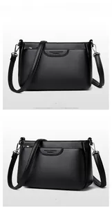 Close-up of black litchi grain leather crossbody bag with adjustable strap and embossed detail