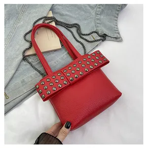 Détail du sac rouge en cuir litchi avec rivets punk et bandoulière en chaîne fine